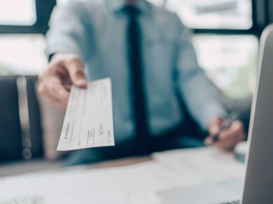 Person in a suit hands over a money cheque.