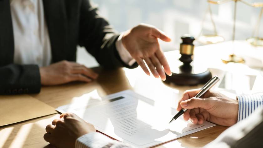 Person signing a legal document with a solicitor.