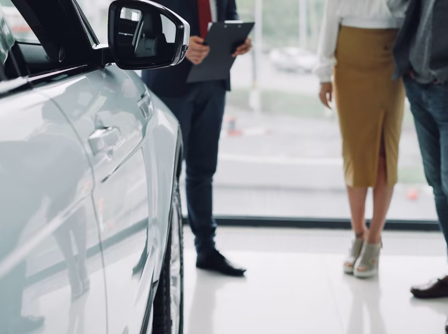 Male and female customers standing next to a car salesperson.